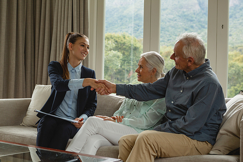 Side view of active senior Caucasian man shaking hands with real estate agent in living room at home