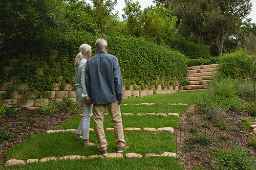Rear view of active senior Caucasian couple standing together hand in hand at garden