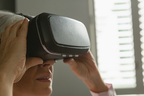 Closed-up of active senior Caucasian woman using virtual reality headset in living room at home