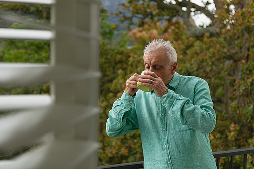 Front view of active senior Caucasian man drinking coffee on the balcony at home