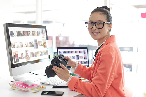 Front view of Asian female graphic designer  while working at desk in a modern office