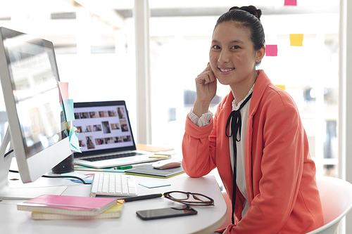 Front view of beautiful Asian female graphic designer  on desk in a modern office