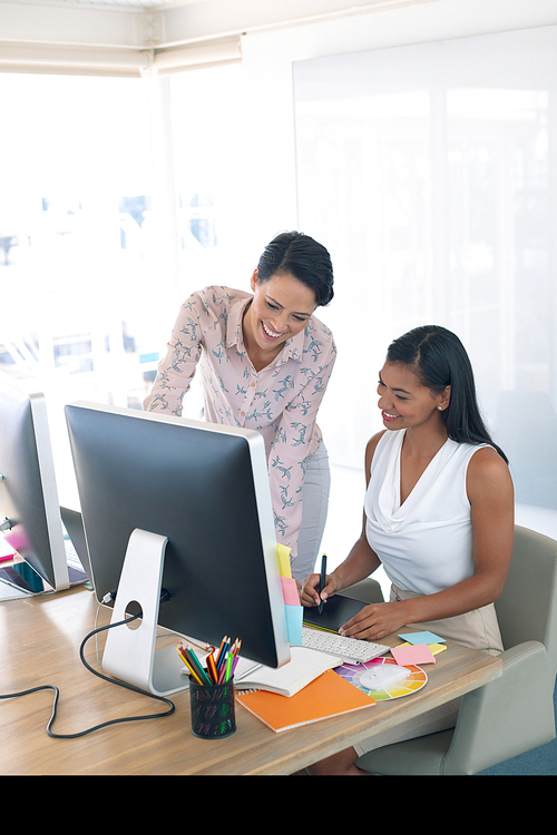 Front view of diverse female graphic designers discussing on computer at desk in a modern office