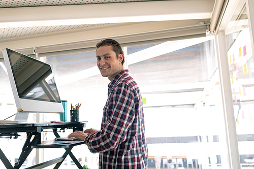 Portrait of Caucasian male graphic designer working on computer at desk in office