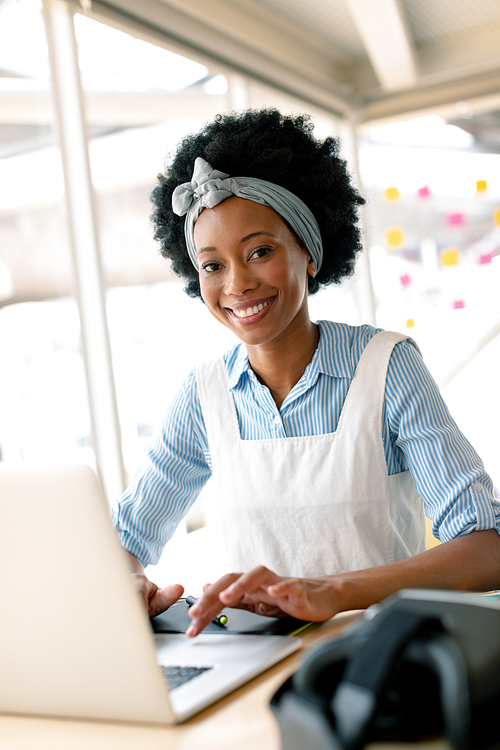 Front view of African american female graphic designer working on laptop at desk in office