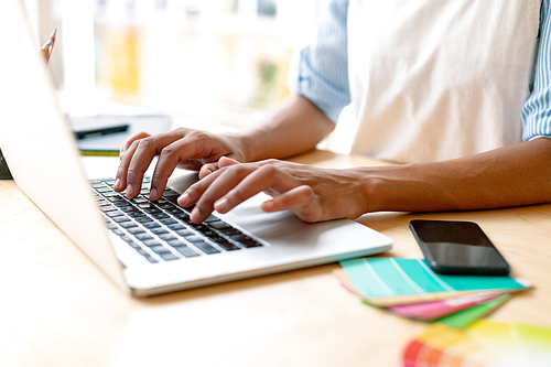 Mid section of African american female graphic designer using laptop at desk in office