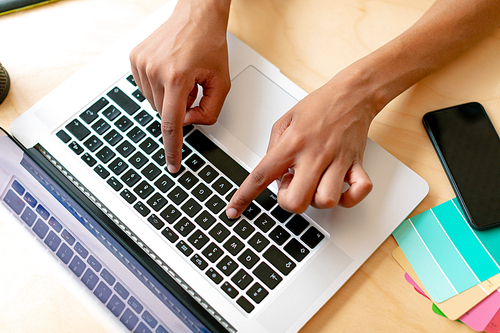 Close-up of female graphic designer using laptop at desk in office