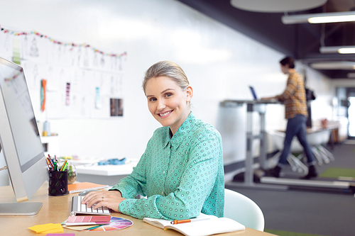 Side view of Caucasian female graphic designer working on computer at desk in office