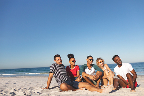 Side view of group of happy diverse friends having fun together on the beach