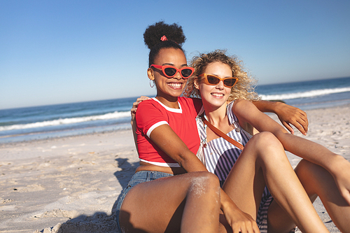 Front view of happy diverse female friends relaxing together on the beach