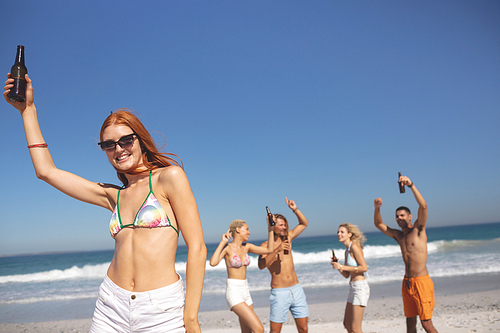 Front view of group of young diverse friends having fun together on the beach