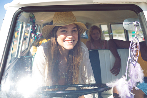 Front view of happy Caucasian woman  while sitting front seat of camper van at beach