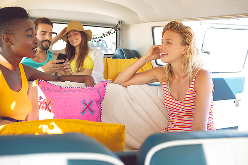 Front view of young group of diverse friends having fun in a camper van at beach