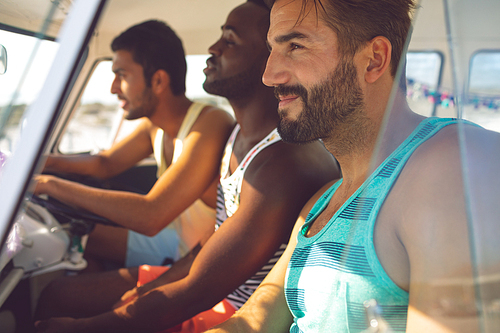 Side view of diverse male friends sitting in a camper van at beach