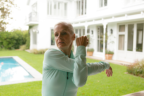 Front view of active senior Caucasian woman exercising in porch at home