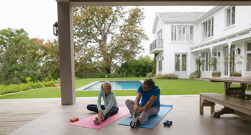 Front view of determined active senior Caucasian couple doing stretching exercise in the porch at home