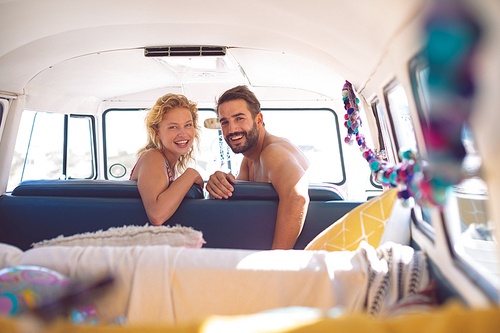 Front view of happy Caucasian couple  in camper van at beach