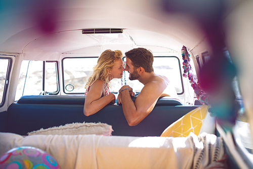 Side view of romantic Caucasian couple sitting in a camper van at beach