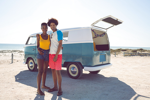 Front view of diverse couple  while standing near camper van at beach
