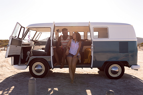 Front view of happy young diverse couple having fun in camper van at beach
