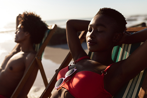Front view of young African-american couple sleeping in a beach chair on the beach