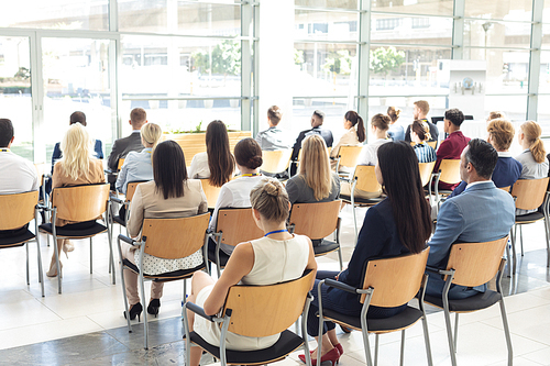 Rear view of group of diverse business people sat in conference room