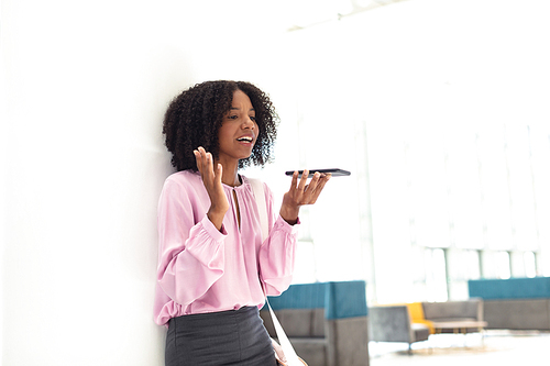 Front view of young pretty African-american employee talking on phone in modern office