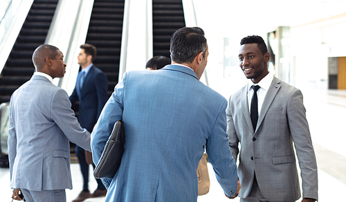 Side view of diverse young executives meeting in front of escalator in modern office