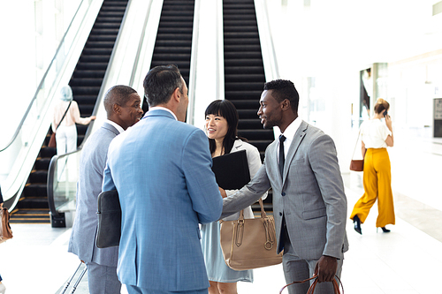 Side view of diverse young executives meeting in front of escalator in modern office