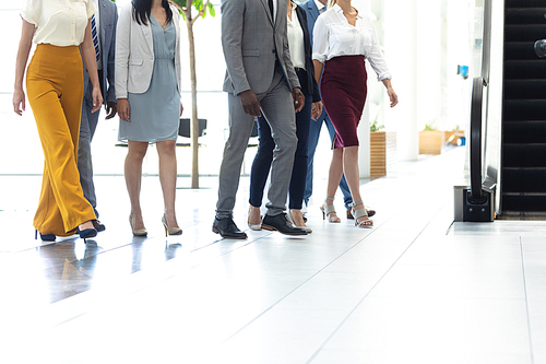 Low section of diverse executives walking in the same direction in hall