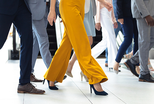 Low section of diverse executives walking in the same direction in hall