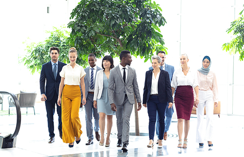 Front view of diverse executives walking in the same direction in hall