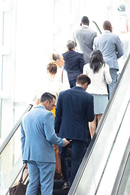 Rear view of diverse business people on escalator in modern office