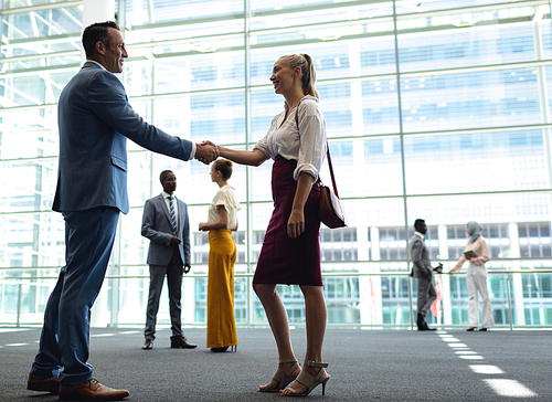 Side view of Caucasian diverse executives shaking hands in modern office