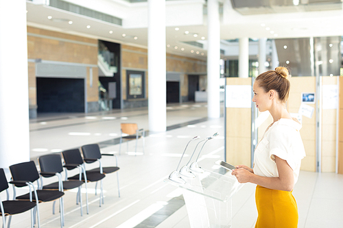 Side view of young Caucasian female executive looking at digital tablet in empty conference room