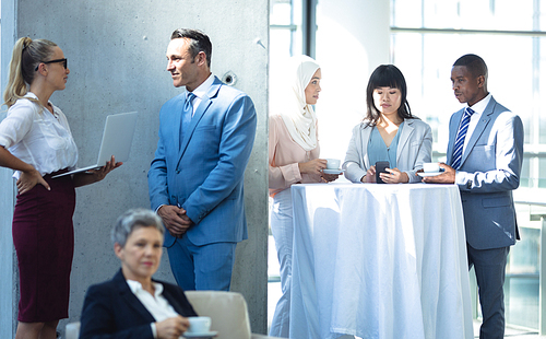 Front view of groups of diverse colleagues interacting with each other in modern office.