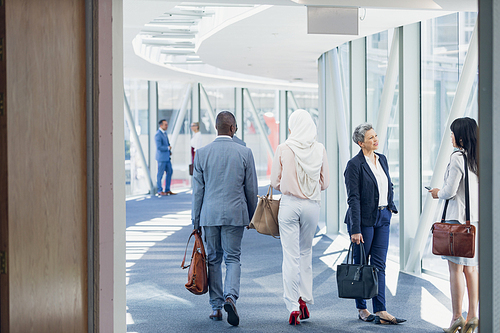 Rear view of business people walking in corridor in modern office