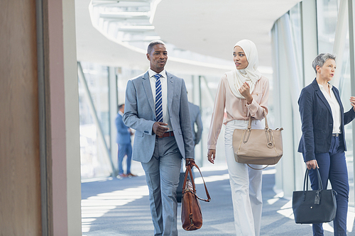 Front view of diverse business people interacting with each other in corridor in modern office