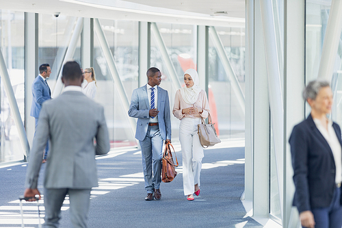 Front view of diverse business people walking in corridor in modern office