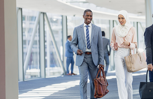 Front view of diverse business people walking in corridor in modern office