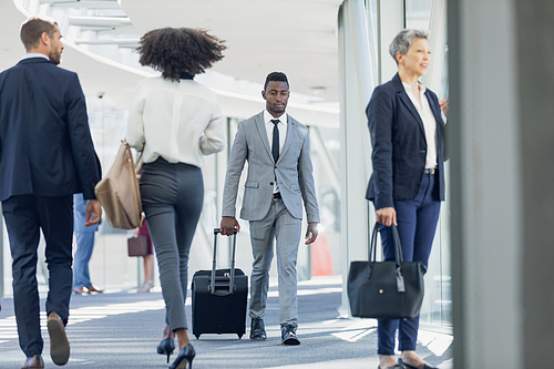 Rear view of diverse business people walking in corridor in modern office