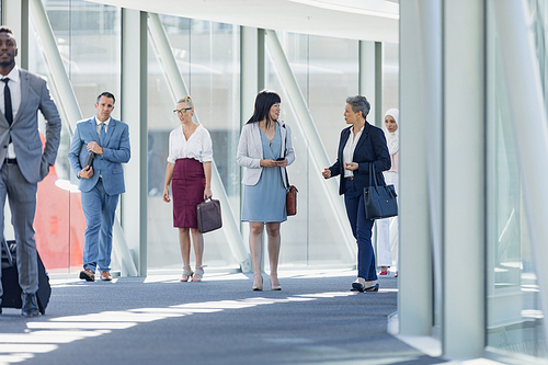 Front view of diverse business people walking in corridor in modern office