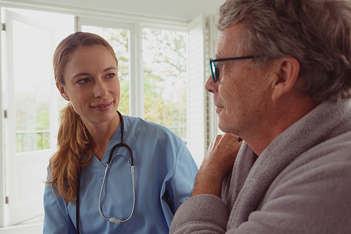 Front view of beautiful Caucasian female doctor consoling active senior man in a comfortable home