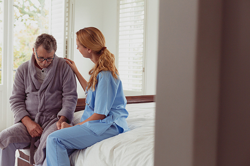 Side view of beautiful Caucasian female doctor consoling active senior man in a comfortable home