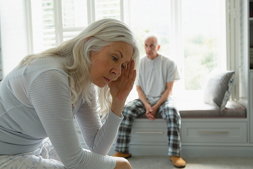 Front view of active senior Caucasian couple ignoring each other in bedroom at home