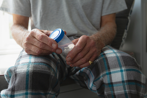 Mid section of active senior Caucasian man taking medicine in bedroom at home