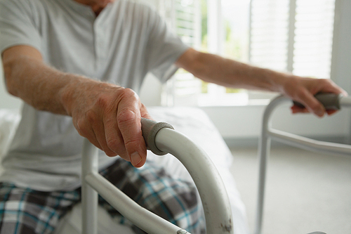 Mid section of senior Caucasian man with walker sitting in bedroom at home