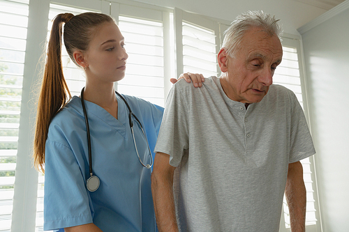 Front view of Caucasian female doctor helping active senior man to walk with walker at home