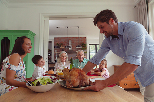 Front view of happy multi-generation Caucasian family having food on dining table at home