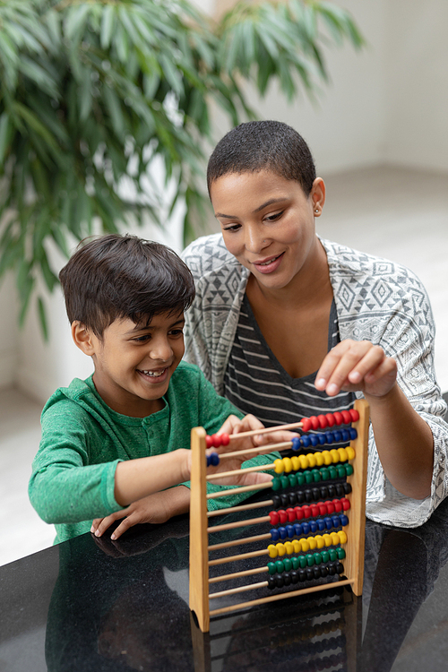Front view of African american mother teaching his son about abacus on a table at home